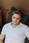 Young man with a beard relaxing on a wooden chair in Barcelona.